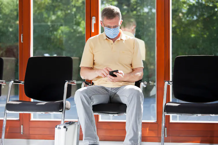Masked man sits in medical waiting room