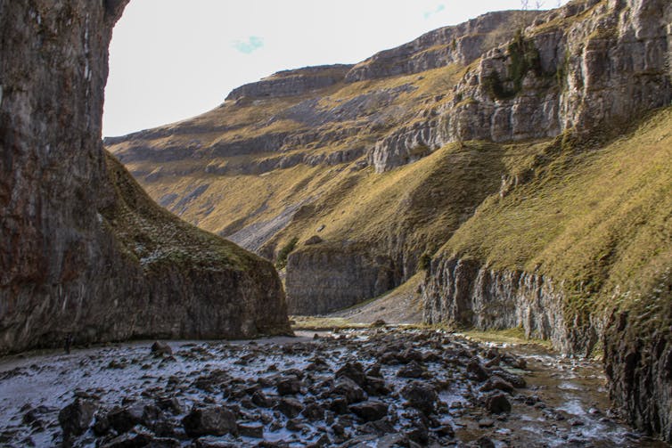 A dramatic green valley covered in rocks.