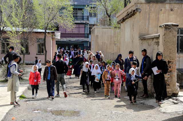 Schoolgirls are led away from their school gates after girls are banned from primary education in Afghanistan, March 2023.