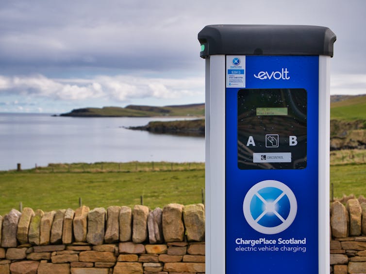 An electric vehicle charging point in a quiet, coastal car park.