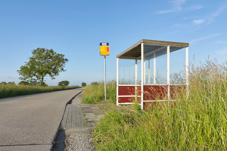 A bus shelter beside an empty rural road.