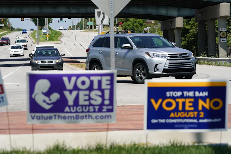 Yes and No signs stand side-by-side on a Kansas highway as cars approach.