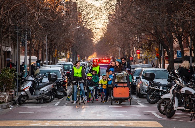 A group of kids and adults cycling through the city.