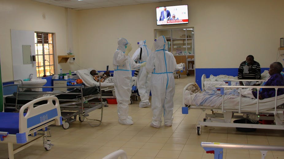 Doctors wearing hazmat suits treating patients in a hospital ward