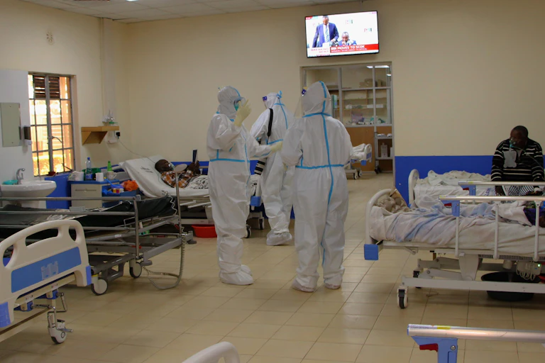 Doctors wearing hazmat suits treating patients in a hospital ward