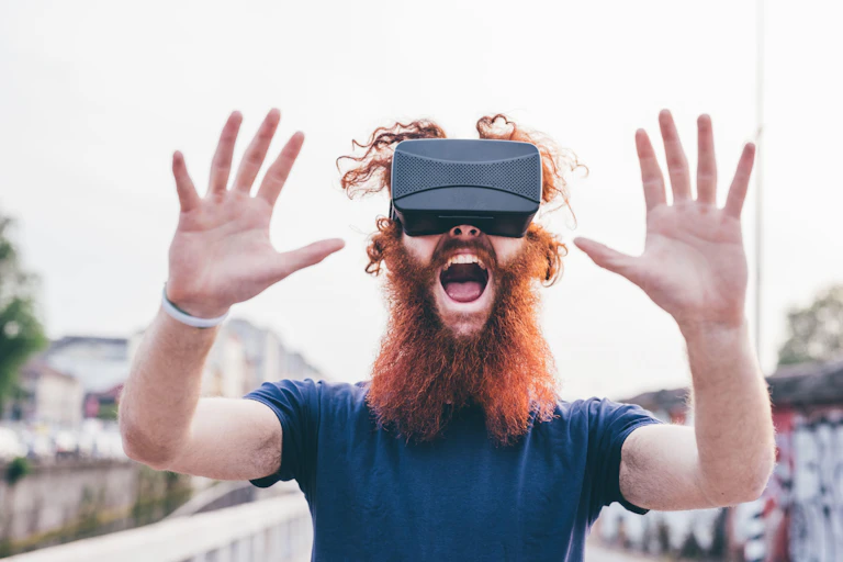 A guy with curly red hair and bushy beard wearing a VR headset in a state of wonder.