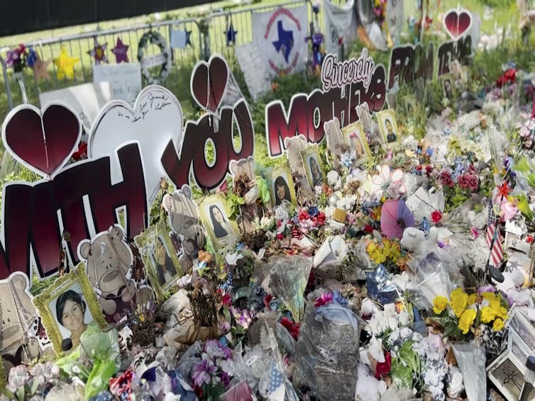 Posters, flowers and photos and heart shapes piled on a lawn.