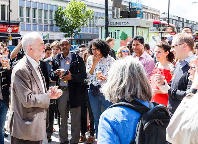 Jeremy Corbyn standing in the middle of a crowd of people on a London street. 