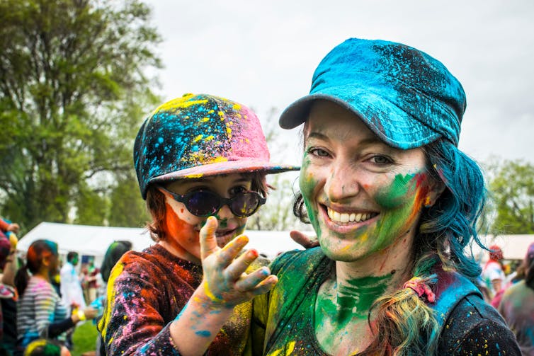 adult woman and child are splattered with colourful paint after colour run activity