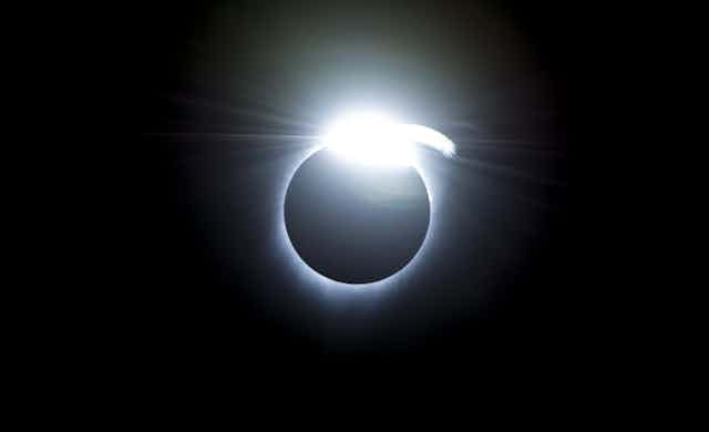 A black circle with a bright white outline and a shining spot on top