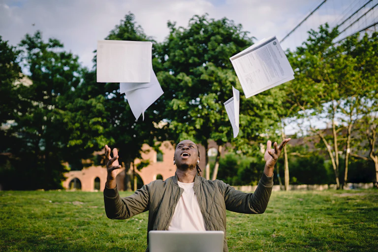 A young man throws papers up in the air.