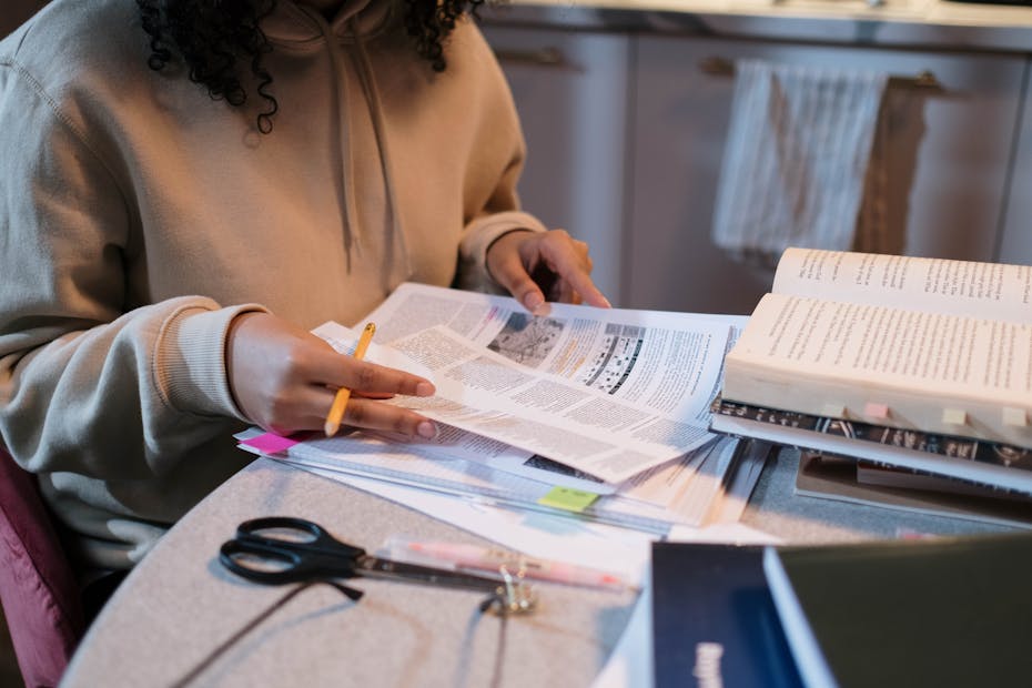 A student working with papers and open books at a desk.