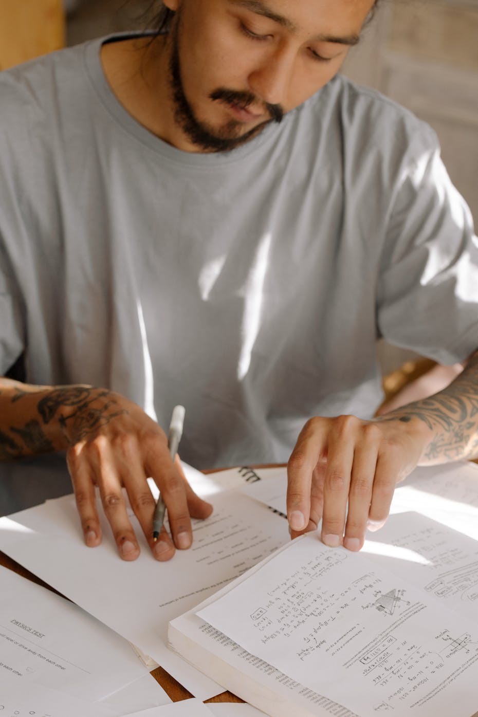 A young man works with papers at a desk.