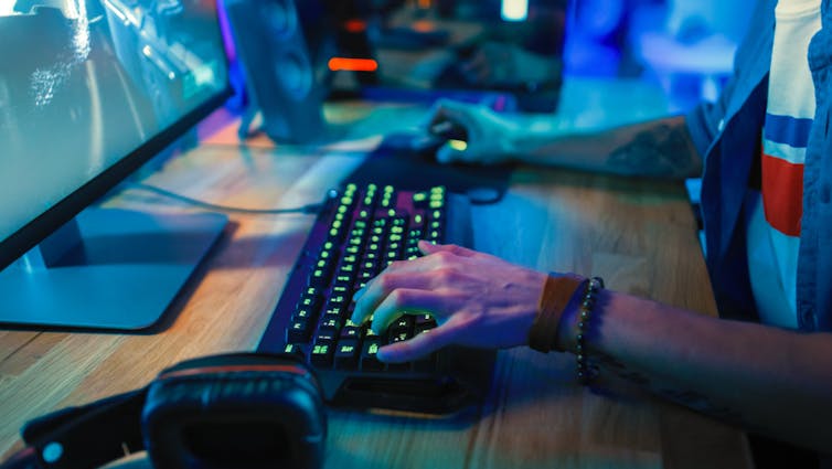 Gros plan sur les mains d’un joueur, travaillant à la fois avec le clavier et sa souris