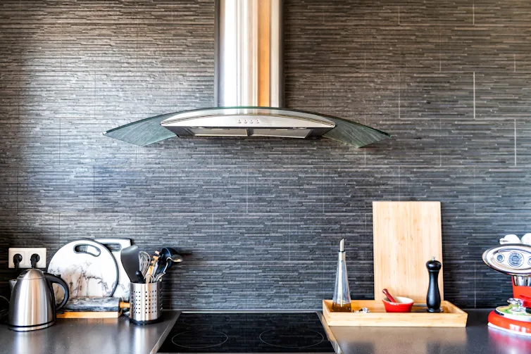 The interior of a kitchen with the cooker hood in the centre.