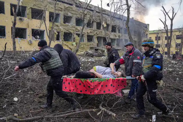 A group of men carry a pregnant woman on a stretcher in Mariupol, Ukraine, March 2022.