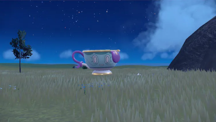A Pokémon shaped like a smiling teacup floats above a field of grass under a dusky sky.