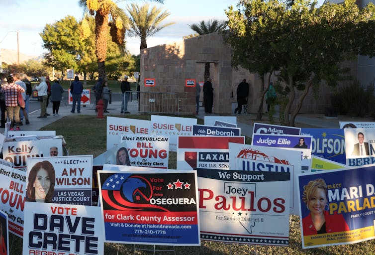 A large collection of colorful campaign signs placed in the ground.