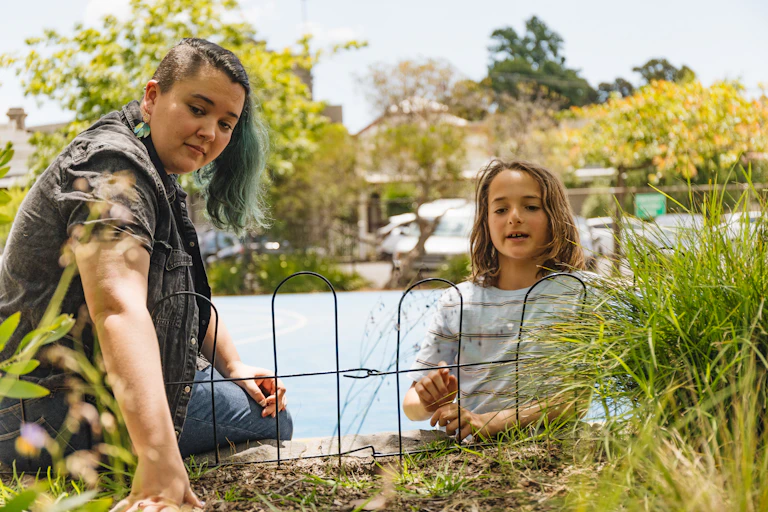 A young Aboriginal educator and researcher with a school student at the site of a new native grasslands planting
