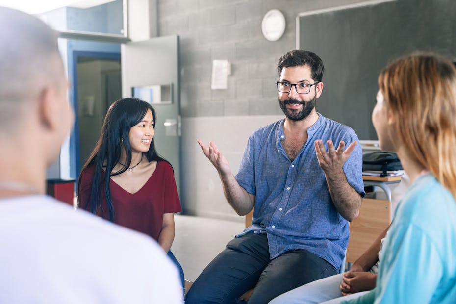 A teacher speaks with students in a classroom.