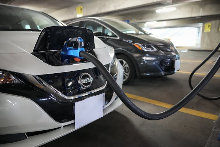 A Nissan Leaf EV charges in a parking garage.