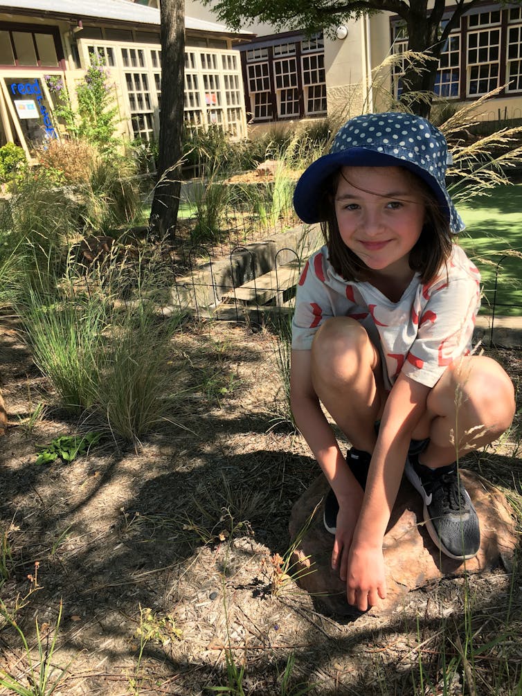 A student crouching in the native garden planted at her school