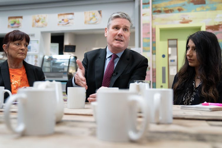 Keir Starmer sitting at a table with women with lots of mugs on the table.