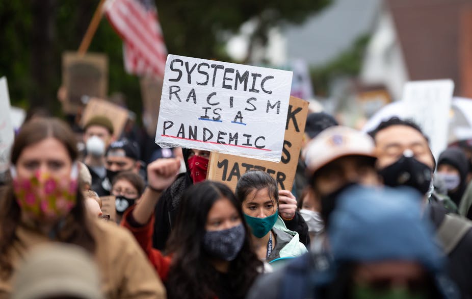 Une manifestante brandi une pancarte dénonçant le racisme systémique à Seattle, États-Unis, le 12 juin 2020.