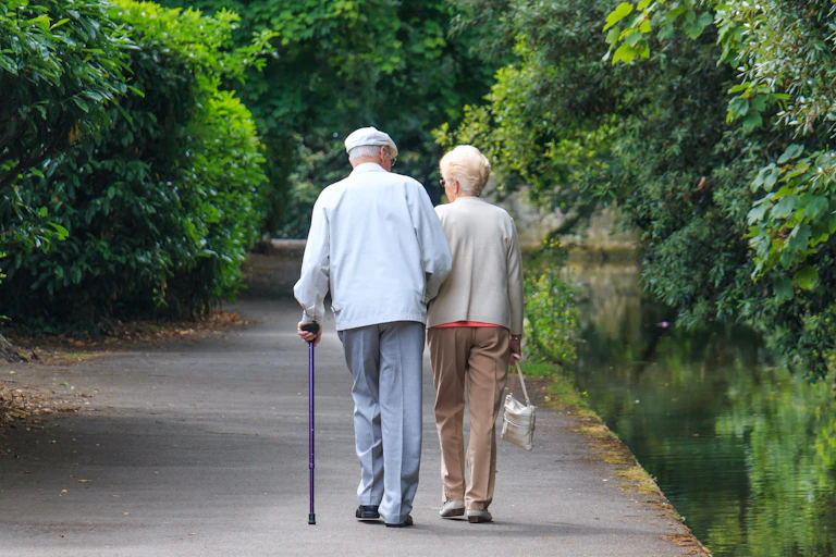 Pareja de ancianos caminando por un parque.