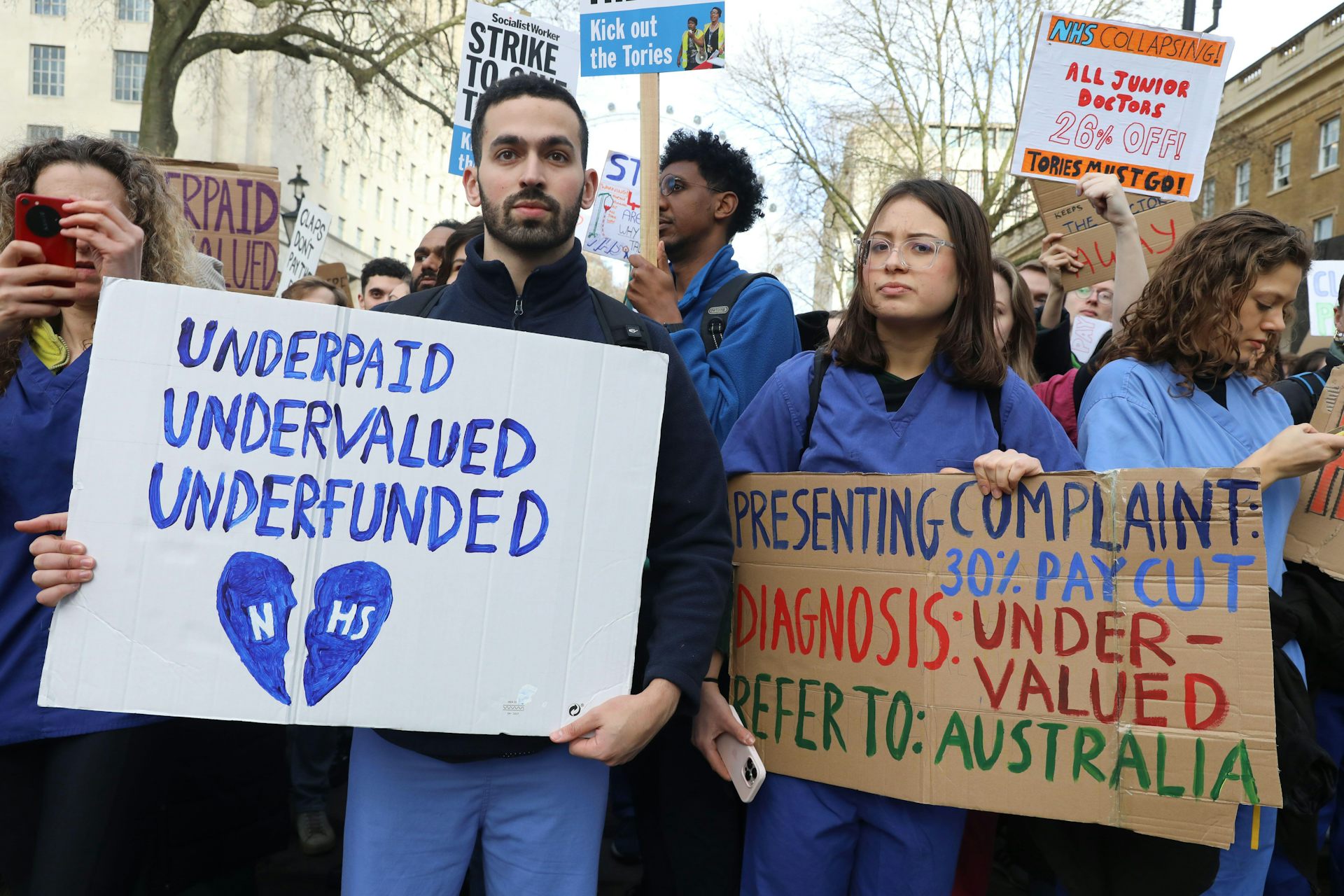 Striking junior doctors hold up signs asking for wage increases.