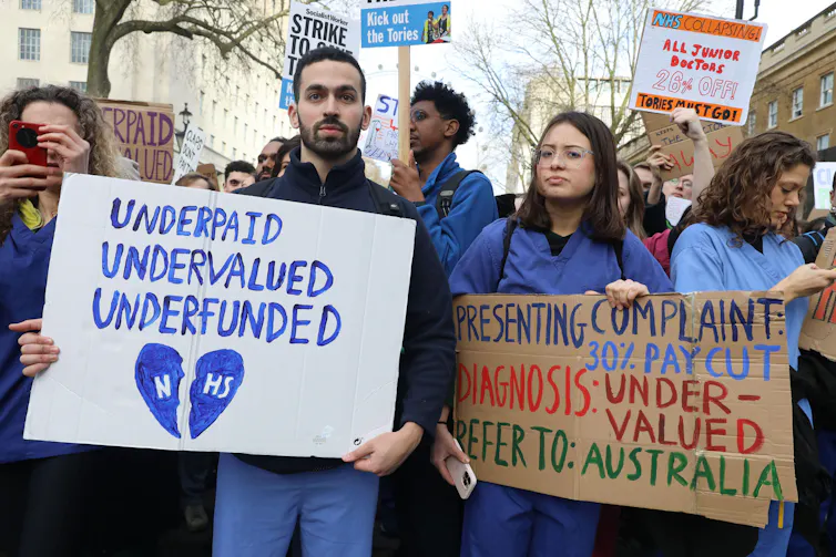 Striking junior doctors hold up signs asking for wage increases.