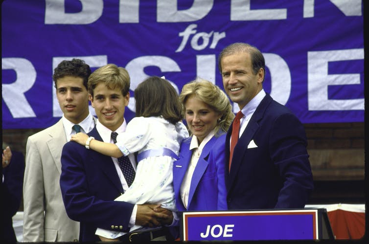 A man and woman with three children, in front of a sign that says 'BIDEN FOR PRESIDENT.'