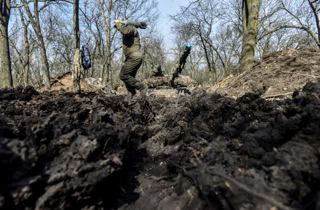 A soldier carries a shell to a tank in a forest in eastern Ukraine.