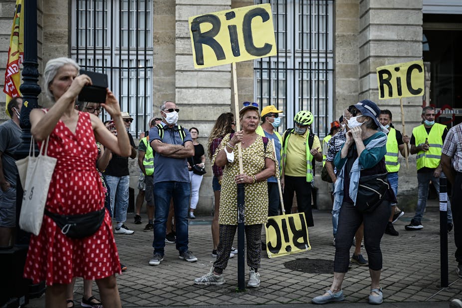 Des manifestants tiennent des pancartes portant l'inscription "RIC" pour "Référendum d'initiative citoyenne" alors qu'ils participent à une manifestation appelée par le mouvement des "Gilets Jaunes" à Bordeaux, dans le sud-ouest de la France, le 12 septembre 2020.