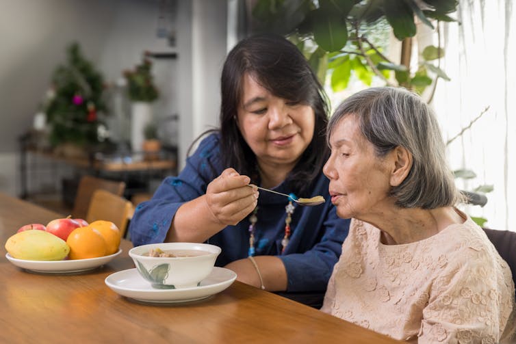 Girl feeding her elderly mother with soup