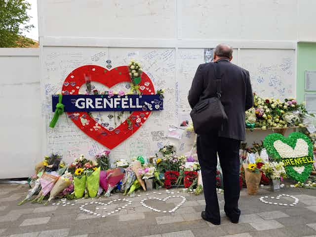 Flowers and notes left under a red heart bearing the word Grenfell.