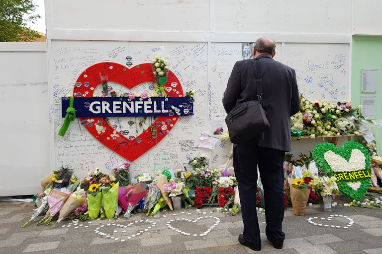 Flowers and notes left under a red heart bearing the word Grenfell.