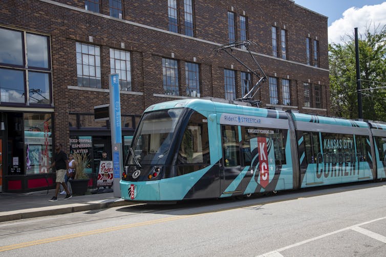 A bright blue light rail train collect passengers