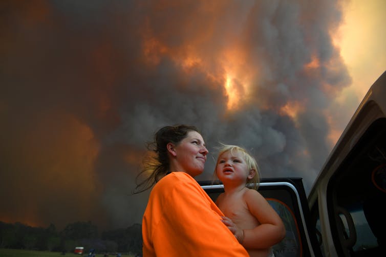 woman and child against smoke-filled sky