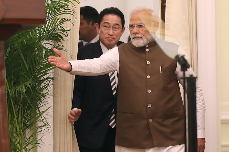 Narendra Modi leads Japanese prime minister Kishida Fumio into a room.