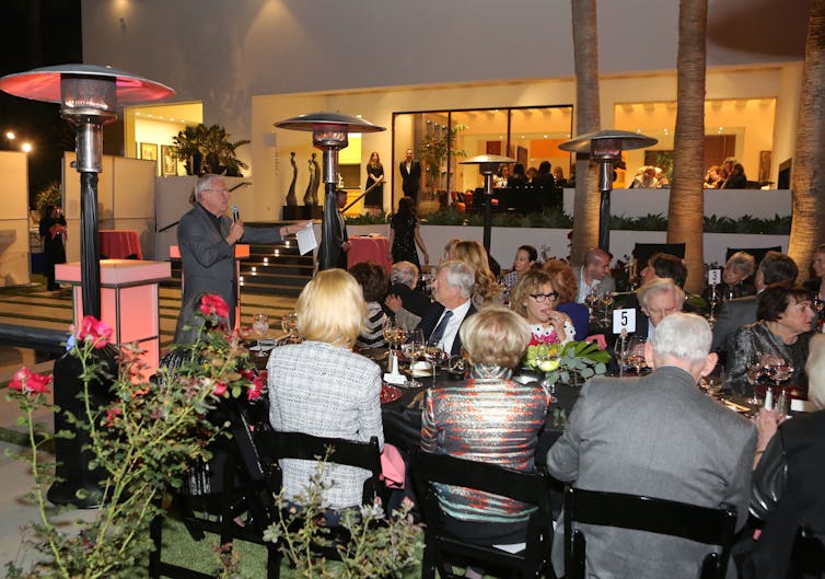 Well-dressed older people gather for a festive meal in a pretty venue.