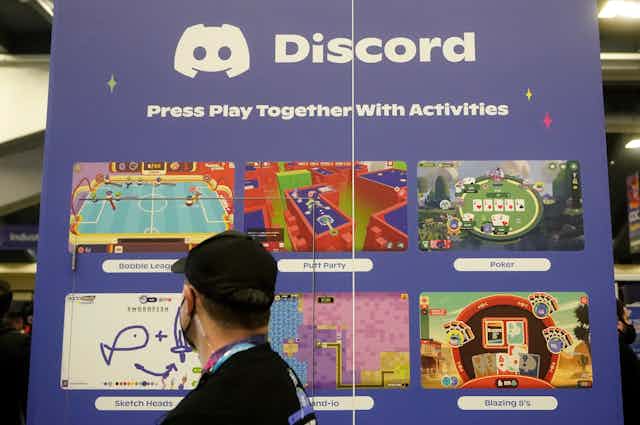 a man at a conference glances up at a display showing images from video games