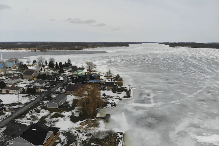 A small snowy town next to a frozen river.