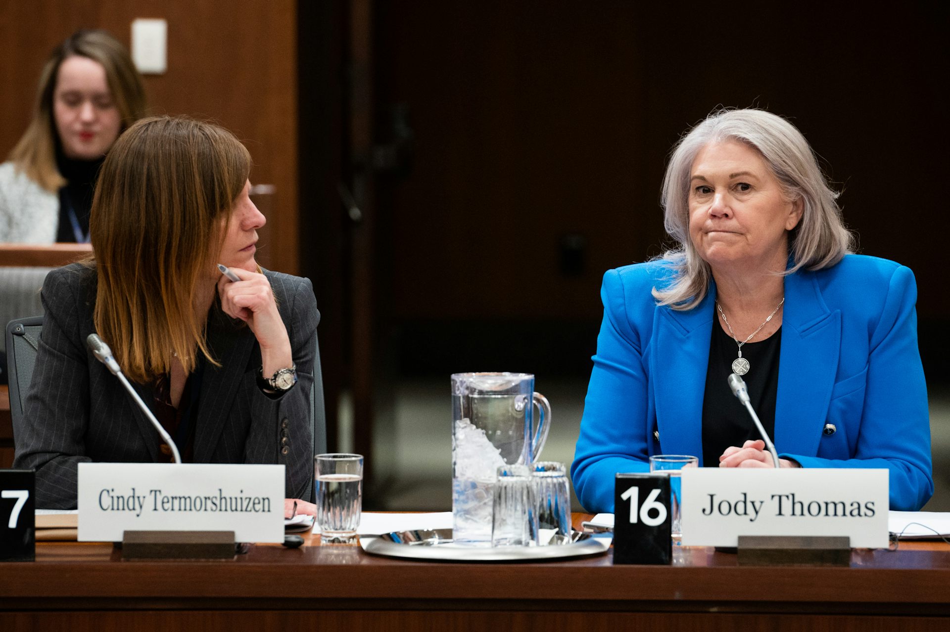 Two women talk as they sit at a table with microphones in front of them.