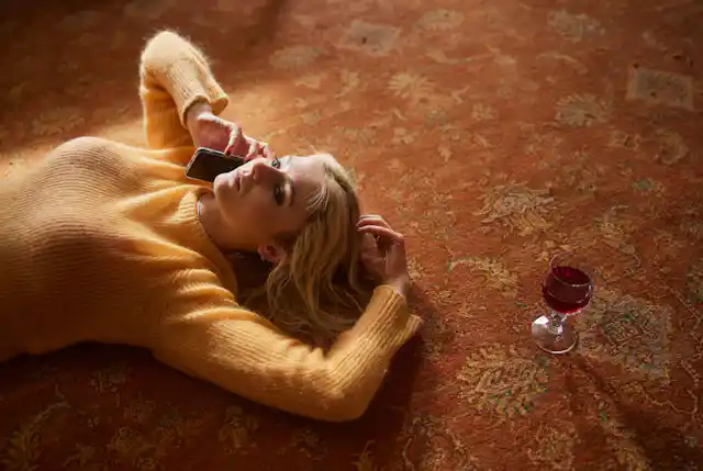 Thomasin McKenzie lying on the floor next to a glass of red wine