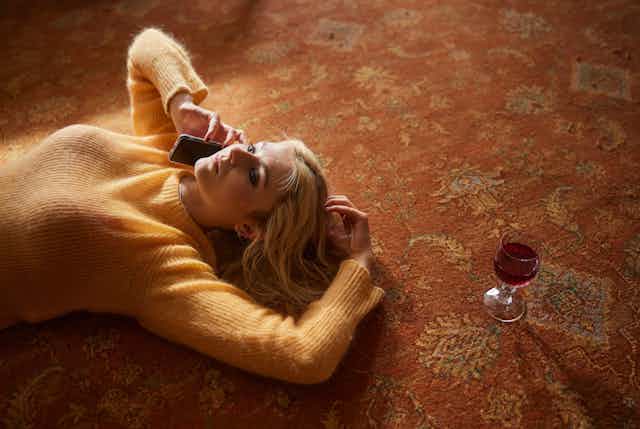 Thomasin McKenzie lying on the floor next to a glass of red wine