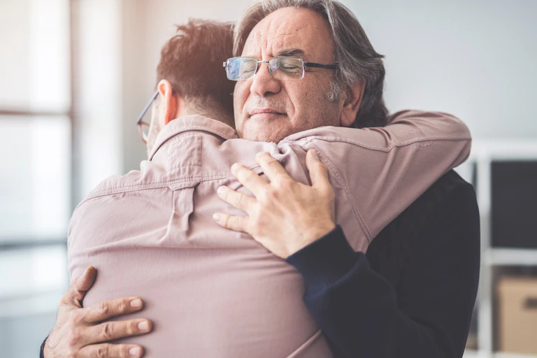 A father hugs his adult son.
