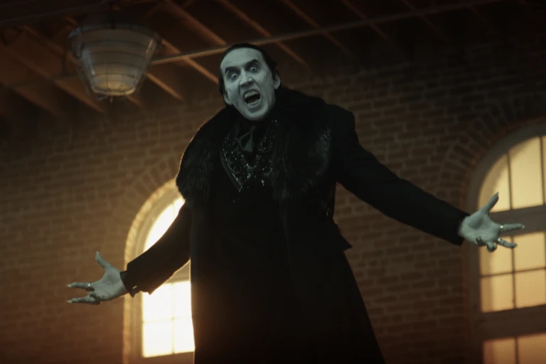 Nicolas Cage as Dracula. He's levitating in the air, arms outstretched, fangs bared.