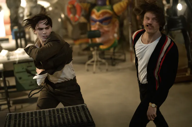 Renfield (Nicholas Hoult) punching a man in a cardigan.