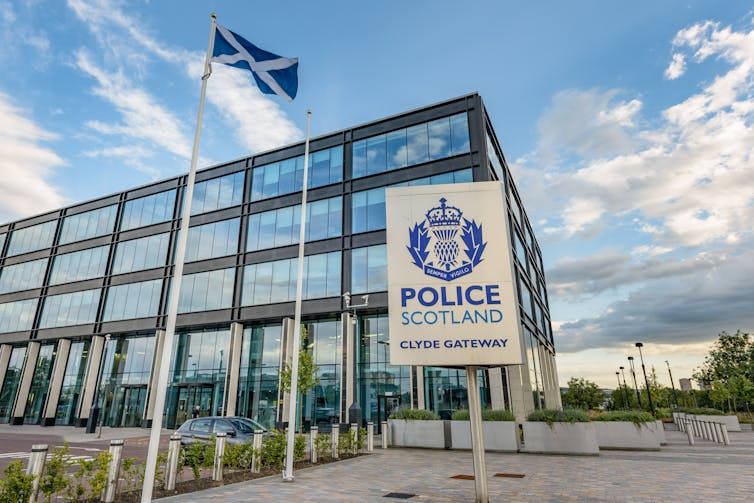 Exterior of Police Scotland Clyde Gateway building, a square, modern building with large glass windows reflecting a blue sky